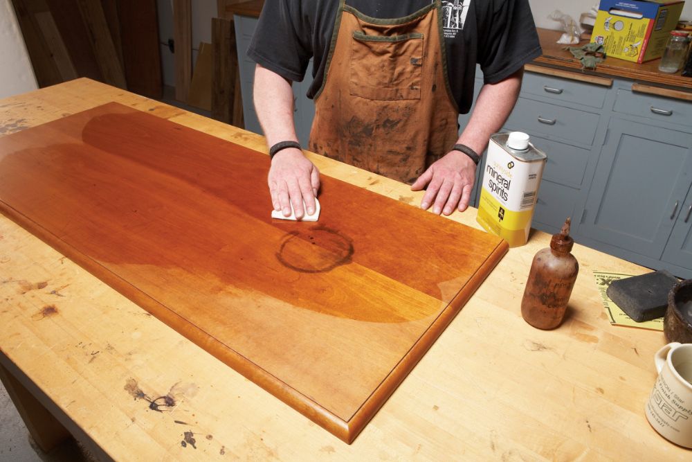 A man is engaged in a task at a wooden table, with tools and materials organized around him.