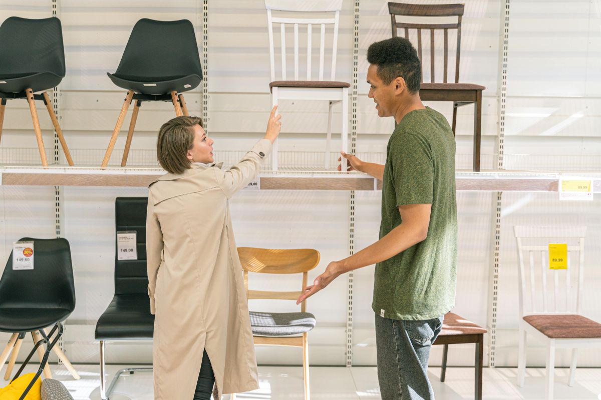 A man and woman stand together in a store, surrounded by various chairs on display.