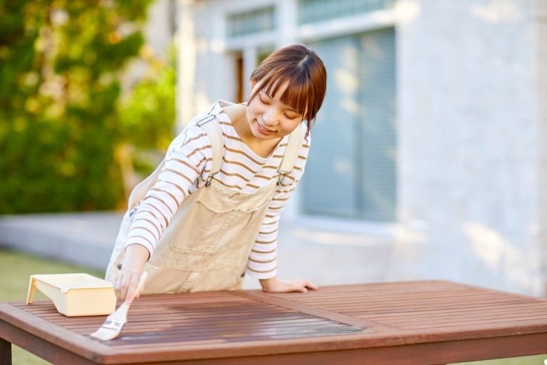 A woman is diligently cleaning a wooden table with a cloth, ensuring it shines and is free of dust.